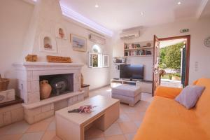 a living room with an orange couch and a fireplace at Villa Ftelias by Villa Plus in Ágios Stéfanos