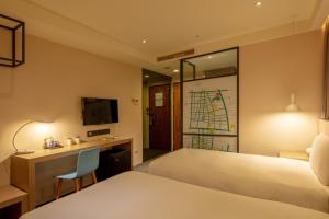 a hotel room with two beds and a desk at Chaiin Hotel - Dongmen in Taipei