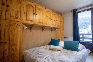 sypialnia z łóżkiem z drewnianymi szafkami i oknem w obiekcie Charming studio with beautiful view - Huez - Welkeys w mieście LʼHuez