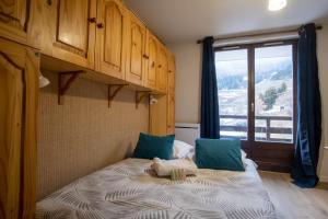 sypialnia z łóżkiem z niebieskimi poduszkami i oknem w obiekcie Charming studio with beautiful view - Huez - Welkeys w mieście LʼHuez