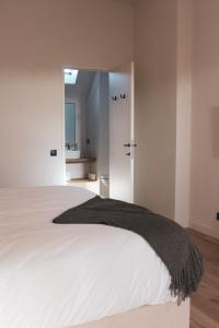 a bedroom with a large white bed and a bathroom at Duisbeke Logies in Oudenaarde