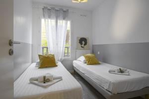 two beds in a white room with yellow pillows at Comfortable apartment with terrace and garden - Welkeys in Bidart