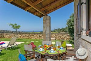 een tafel en stoelen op een patio met uitzicht op de oceaan bij Villa Hara Faragi by Villa Plus in Giannoudi