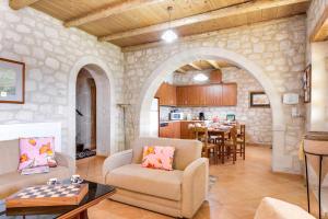 een woonkamer en een keuken met een stenen muur bij Villa Hara Faragi by Villa Plus in Giannoudi