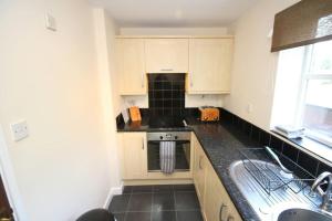 a kitchen with a sink and a stove top oven at Modern 2 bed flat on marina development! in Saint Peters