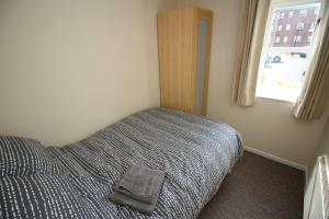 a bedroom with a bed with a gray blanket and a window at Modern 2 bed flat on marina development! in Saint Peters
