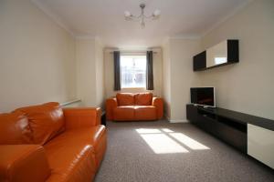 a living room with an orange couch and a television at Modern 2 bed flat on marina development! in Saint Peters