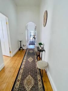 a hallway with a rug and a table and a mirror at Modern Victorian 4 bedroom home in trendy Observatory. in Cape Town
