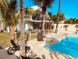 a house with a swimming pool and palm trees at LE NID TROPICAL in Étang-Salé les Bains