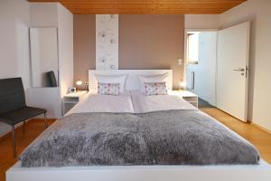 a bedroom with a large white bed and a chair at Gästehaus Huber in Immenstaad am Bodensee