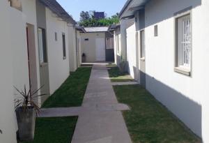 a walkway between two buildings with grass at Departamentos Araoz in Salta