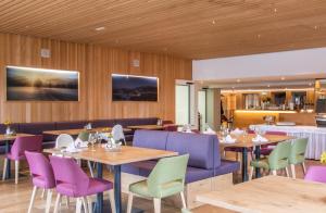 un restaurante con mesas y sillas de color púrpura y verde en Hotel Gasthof Adler, en Lingenau
