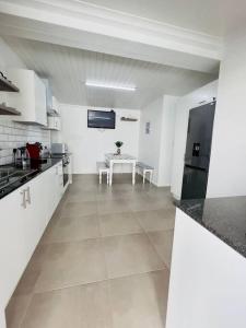 Una gran cocina blanca con mesa y encimera. en Modern Victorian 4 bedroom home in trendy Observatory., en Ciudad del Cabo