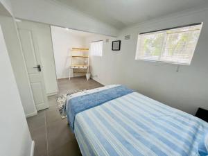 a small bedroom with a bed and a window at Modern Victorian 4 bedroom home in trendy Observatory. in Cape Town