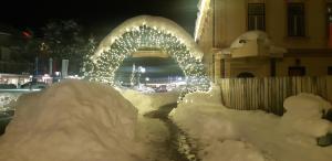a building covered in snow with an arch with lights at Sunny place in Kranjska Gora