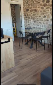 una mesa y sillas en una habitación con una pared de piedra en Apartamento El Olivo, en Villabáñez