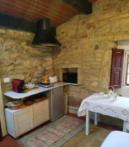 cocina con paredes de piedra, fogones y mesa en Casita en Domaio - Moaña en Moaña