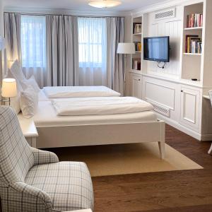 a white bedroom with a bed and a tv at Hotel-Restaurant Anne-Sophie in Künzelsau