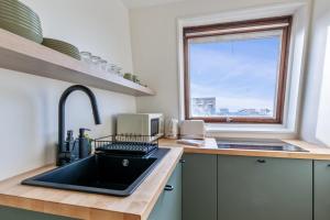 uma cozinha com um lavatório preto e uma janela em Brand new studio with sea view in the Deauville port - Welkeys em Deauville