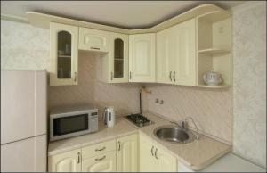 a kitchen with white cabinets and a sink and a microwave at Apartments Morskaya 31 in Saint Petersburg
