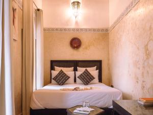 um quarto com uma cama branca, um candeeiro e uma mesa em Riad Amegrad em Marrakech