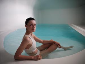Eine junge Frau, die im Schwimmbad sitzt. in der Unterkunft Abyss in Oia