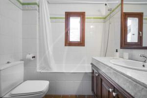 a white bathroom with a toilet and a sink at Tanau 1700 by SeaMount Rentals in Naut Aran