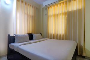 a bedroom with a bed with white sheets and a window at FabExpress Buddha Residency in Patna