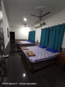 two beds in a room with blue curtains at Kulswamini home stay in Malvan