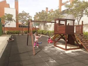 Una niña está jugando en un columpio en Chalet Familiar Jardín a 15 min centro y Warner en Rivas-Vaciamadrid