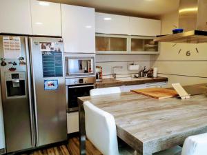 a kitchen with a wooden table and a stainless steel refrigerator at Chalet Familiar Jardín a 15 min centro y Warner in Rivas-Vaciamadrid