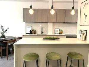 a kitchen with a counter with two green stools at 2 Bedroom Penthouse Apartment in London