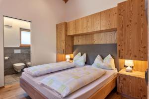 Schlafzimmer mit einem großen Bett mit einem Kopfteil aus Holz in der Unterkunft Guntschöllerhof Mendelkamm in Völs am Schlern