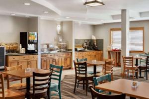 a restaurant with tables and chairs and a kitchen at AmericInn by Wyndham Laramie Near University of Wyoming in Laramie