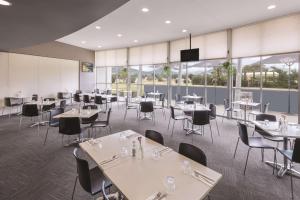 uma sala de jantar com mesas, cadeiras e janelas em Travelodge Hotel Hobart Airport em Cambridge
