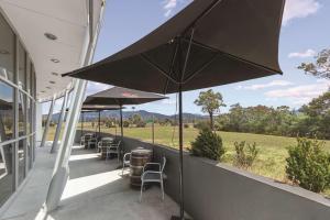 a patio with tables and chairs and an umbrella at Travelodge Hotel Hobart Airport in Cambridge