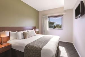 um quarto de hotel com uma cama grande e uma janela em Travelodge Hotel Hobart Airport em Cambridge