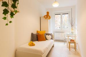 ein kleines Schlafzimmer mit einem Bett mit gelben und orangefarbenen Kissen in der Unterkunft GoodVibesHome in Mailand