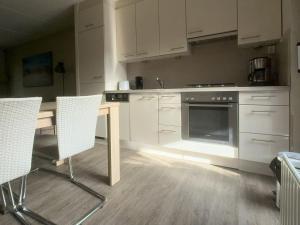 a kitchen with white cabinets and a table and chairs at Spaanse Galeienstraat 75 in Retranchement
