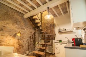 a kitchen with a spiral staircase and a brick wall at Umbrian Concierge - La Corte del Grillo in Perugia