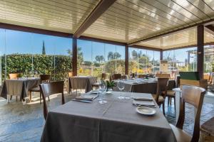 a restaurant with tables and chairs and large windows at Hotel Borgo Di Cortefreda - Place of Charme in Tavarnelle Val di Pesa