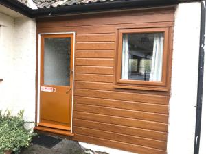 a wooden shed with a door and a window at Court Farm Holiday Bungalows Ltd in Watchet