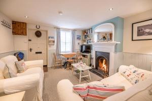 a living room with white furniture and a fireplace at Fishermans Cottage in Aldeburgh
