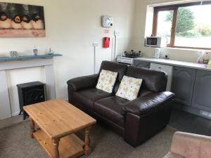 a living room with a leather couch and a table at Court Farm Holiday Bungalows Ltd in Watchet