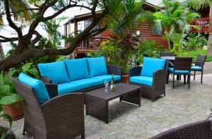 un patio con sillas de mimbre, sofás azules y una mesa. en West Bay Lodge and Spa en West Bay