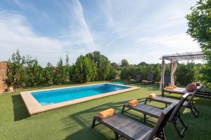 a backyard with a swimming pool and two chairs at Can Miquel Porro in Llubí