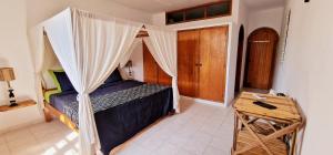 a bedroom with a canopy bed and a wooden table at Ginger Villa Somone in Somone