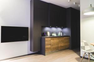 a kitchen with black cabinets and a flat screen tv at Stylish flat in Rīga