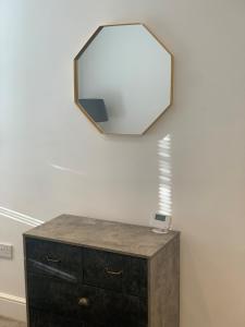 a mirror on a wall above a dresser with a drawer at Alsager Town Centre Apartment in Alsager