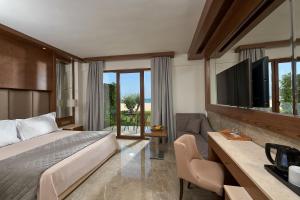 una camera d'albergo con letto e TV di Mediterranean Village Hotel & Spa a Paralia Katerinis
